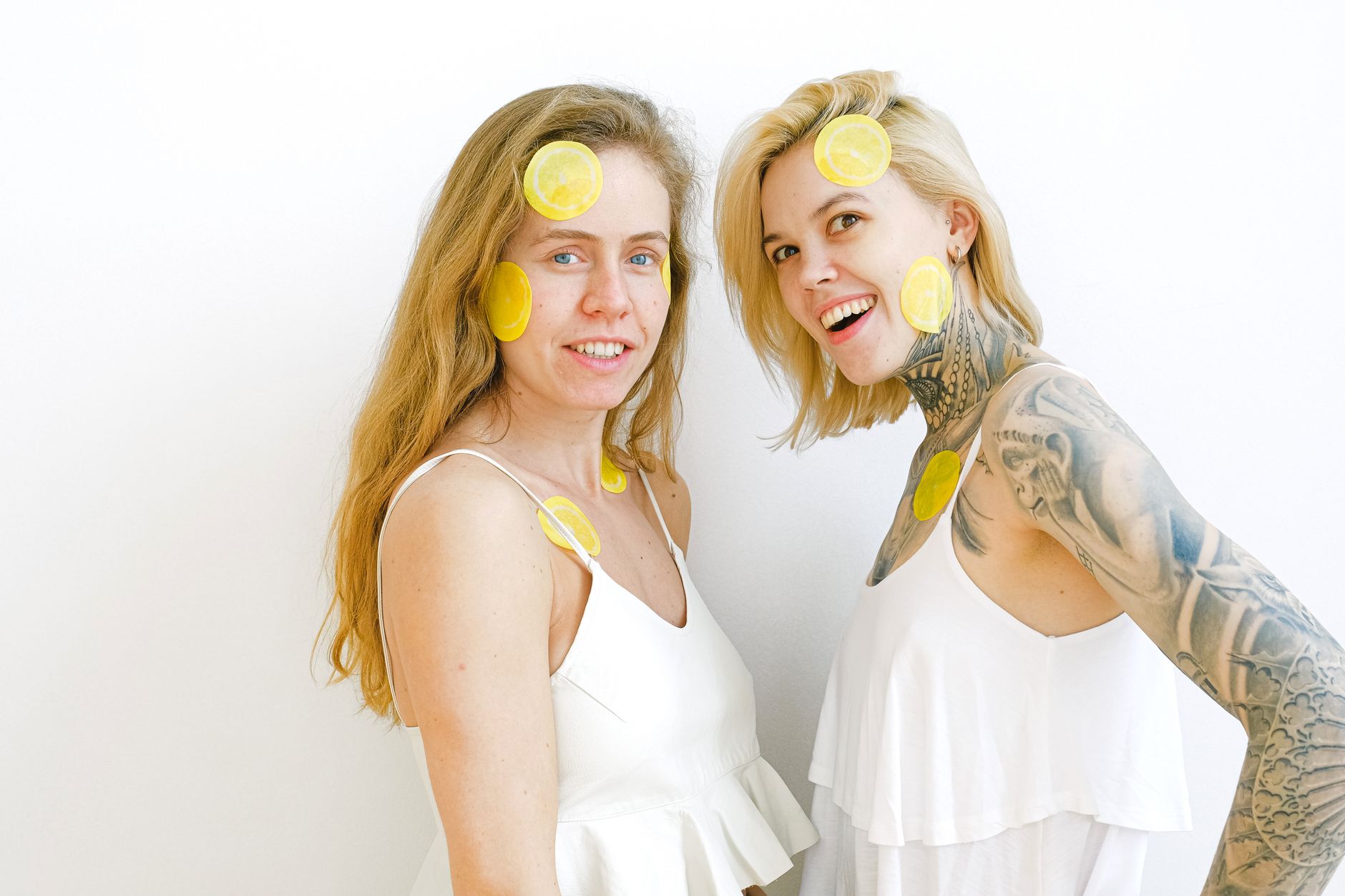 Two women laughing together joyfully with lemon face masks on