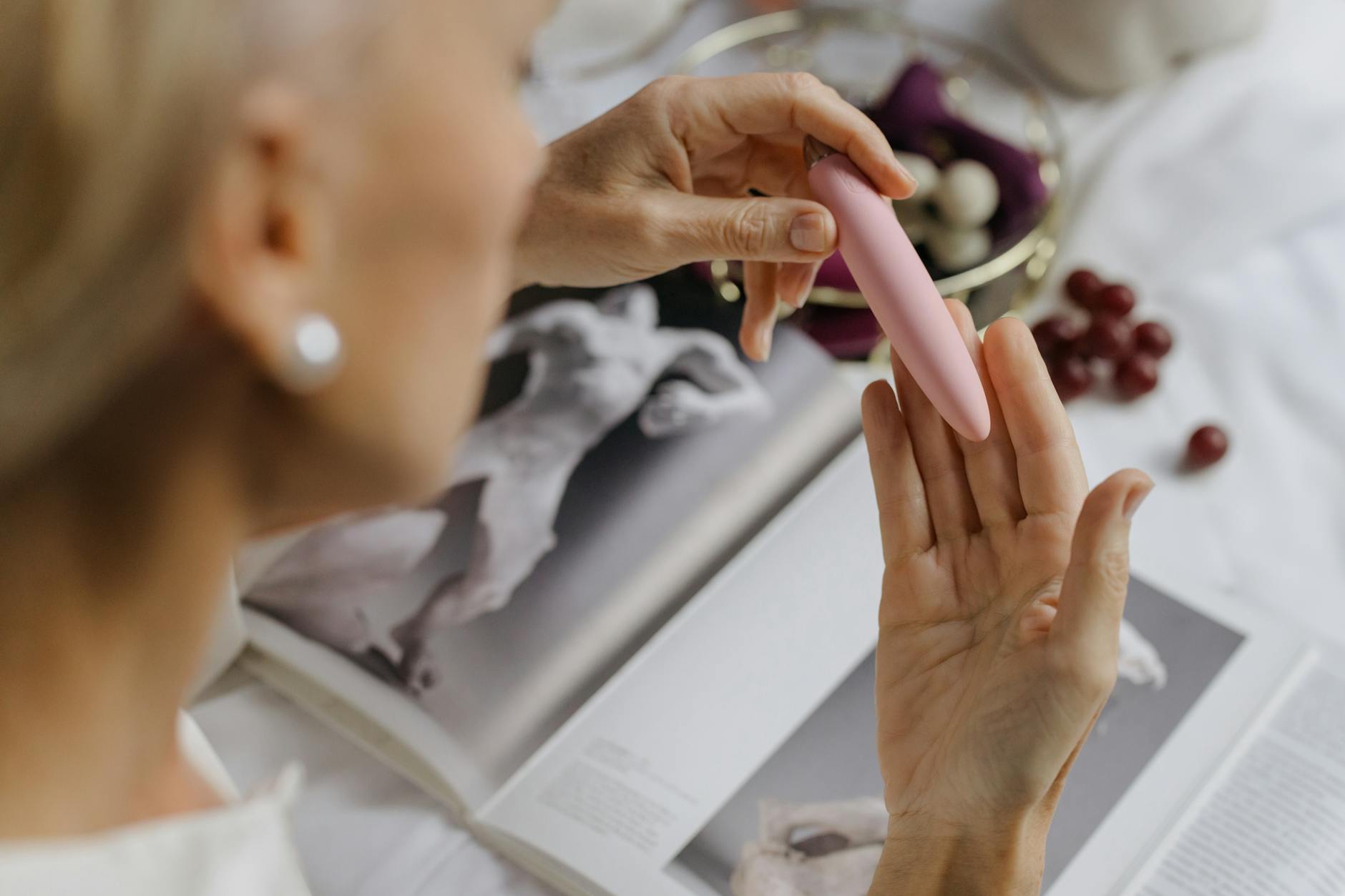 Close-up of a hand holding a lemon clitoral vibrator, with intimate personal items in soft focus background
